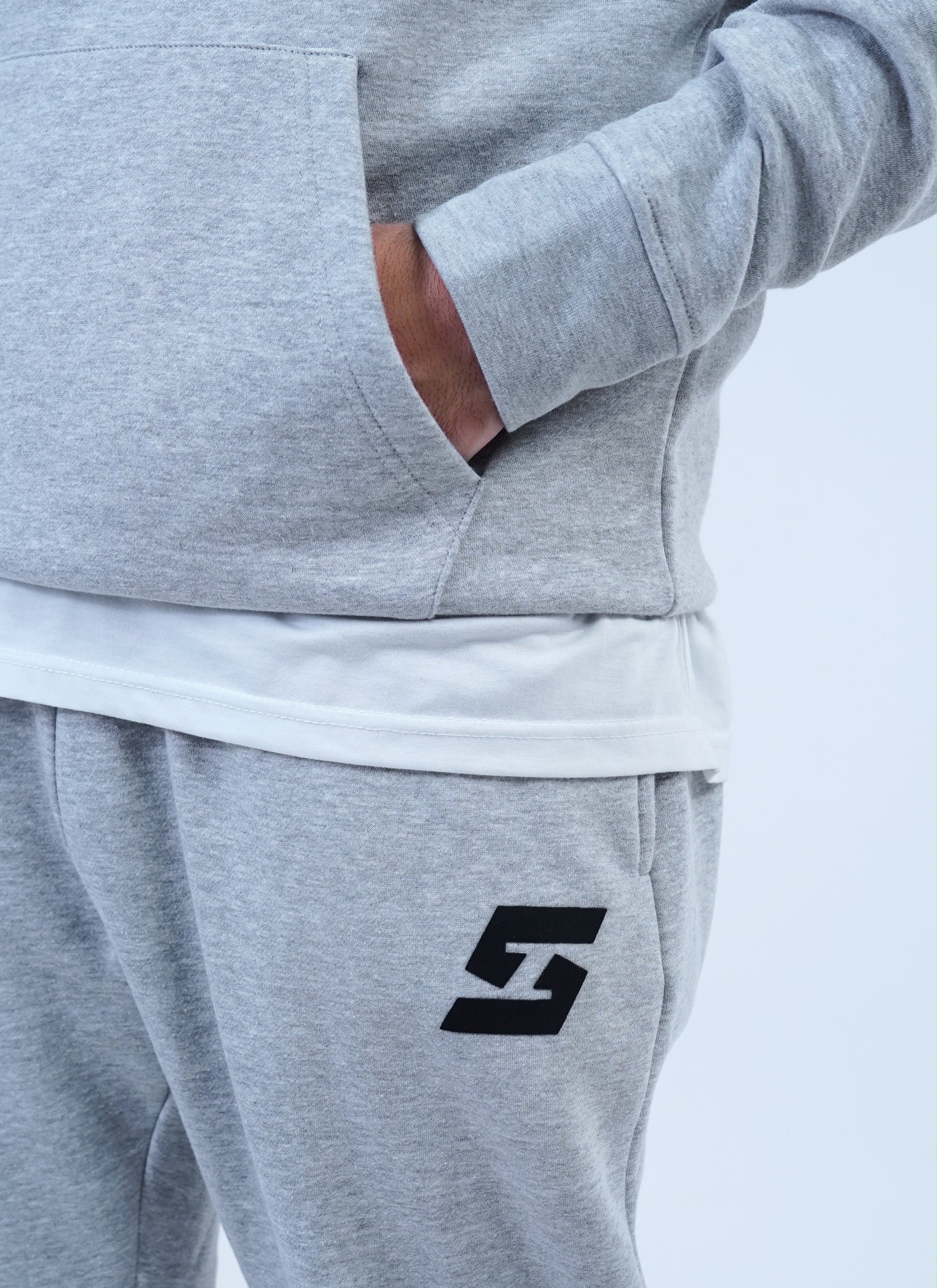 Grey fleece men's jogger tracksuit with pullover hoodie and logo, featuring snug fit sweatpants for stylish casual wear.